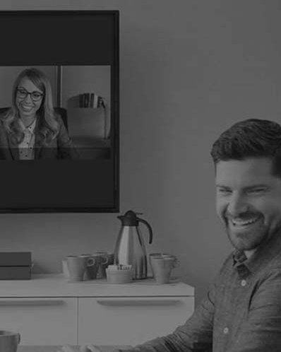 Drei Personen sitzen im Meetingraum vor deinem Fernseher während ein Meeting abläuft